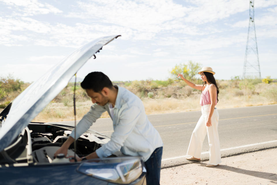 Latin young woman making autostop and asking for a ride after her boyfriend's car broke down