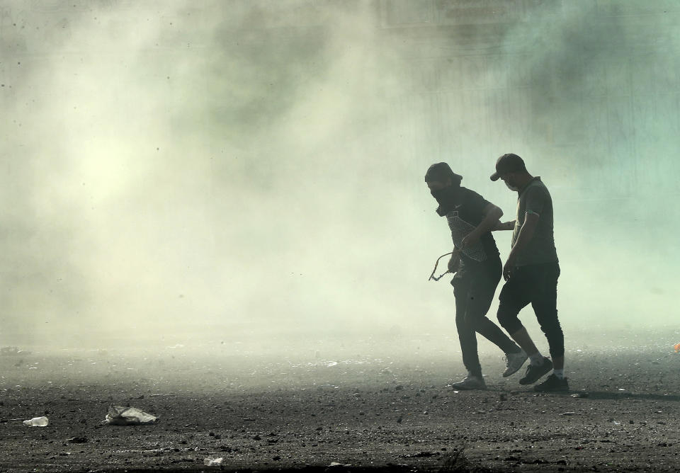 Anti-government protesters are engulfed in tear gas fired by Iraqi security forces during clashes between Iraqi security forces and anti-government protesters, in Baghdad, Iraq, Monday, Nov. 11, 2019. (AP Photo/Hadi Mizban)