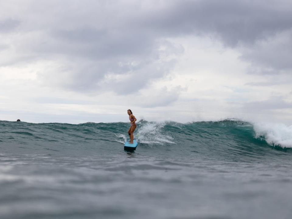A woman on a blue surfboard surfing on a wave in Hawaii