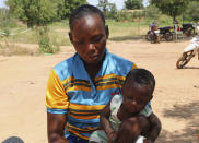 Adama Tapsoba sits with her child on her lap outside a small clinic in Gampela village on the outskirts of Burkina Faso's capital, Ouagadougou, Saturday Oct. 10, 2020. Tapsoba walks four hours under scorching sun to reach the Gampela clinic and waits another four hours for her 5-month-old son to get his routine baby immunizations. She says she thinks that participating in a widespread coronavirus inoculation program will be challenging in her part of the world. The public health clinic responsible for serving approximately 11,000 people, did not have a working fridge for almost a year. (AP Photo/Sam Mednick)