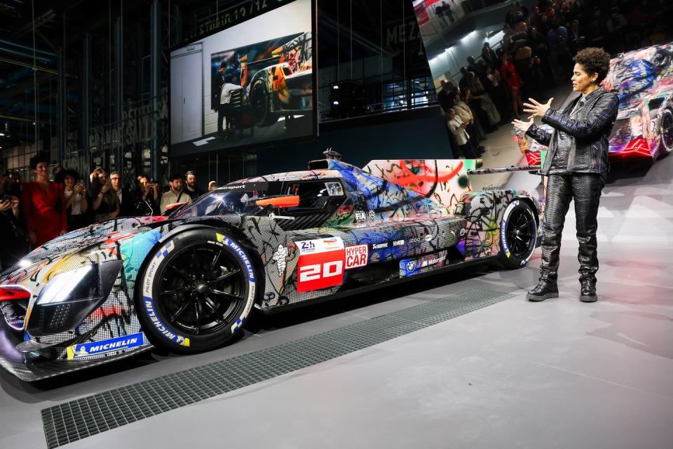 a person standing next to a race car on display