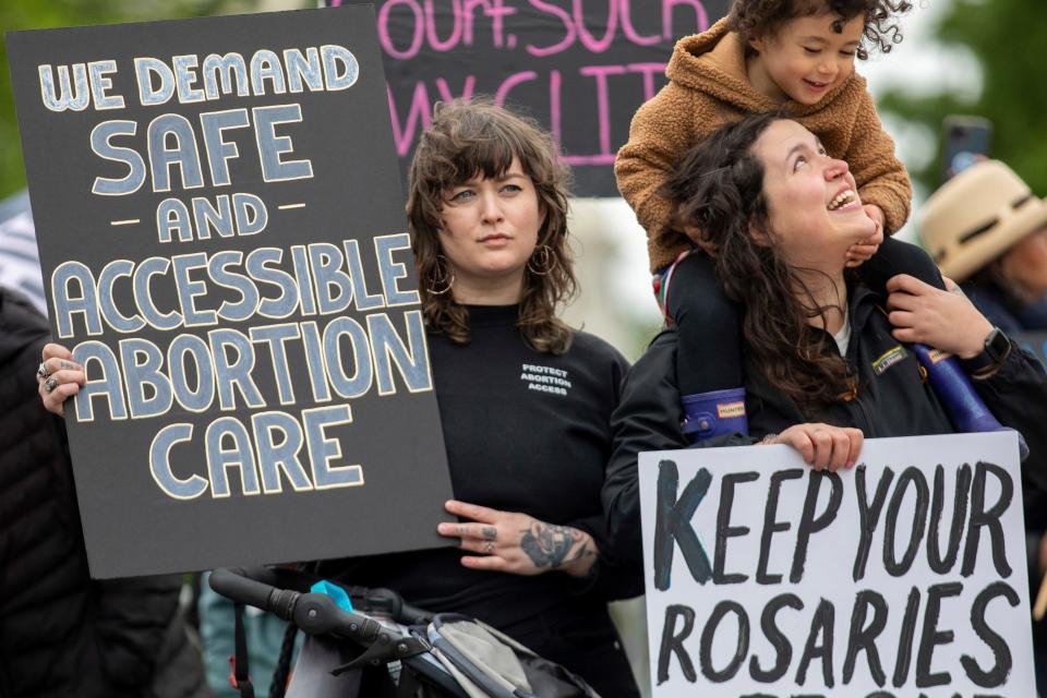 Abortion-rights protesters Holly Strandberg, left, and Kara Coulombe and her daughter Hana Uyehara, 3, hold signs during a demonstration outside of the U.S. Supreme Court in Washington, Sunday, May 8, 2022.