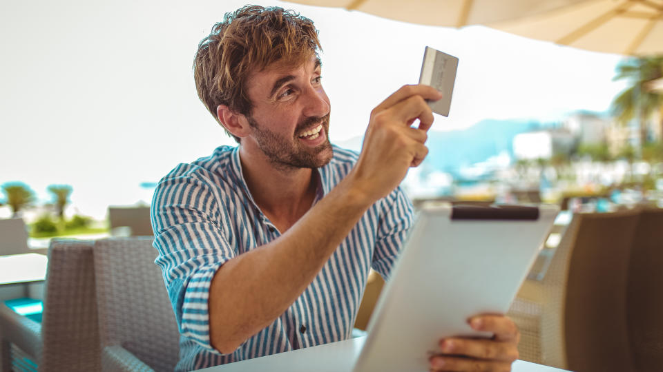 Portrait of cheerful man paying for order with credit card in cafe.