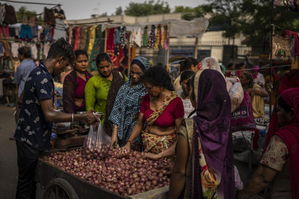 A roadside vendor packs onions in plastic bags as women shop at a weekly market in New Delhi, India, Wednesday, June 29, 2022. India banned some single-use or disposable plastic products Friday as a part of a longer federal plan to phase out the ubiquitous material in the nation of nearly 1.4 billion people. (AP Photo/Altaf Qadri)