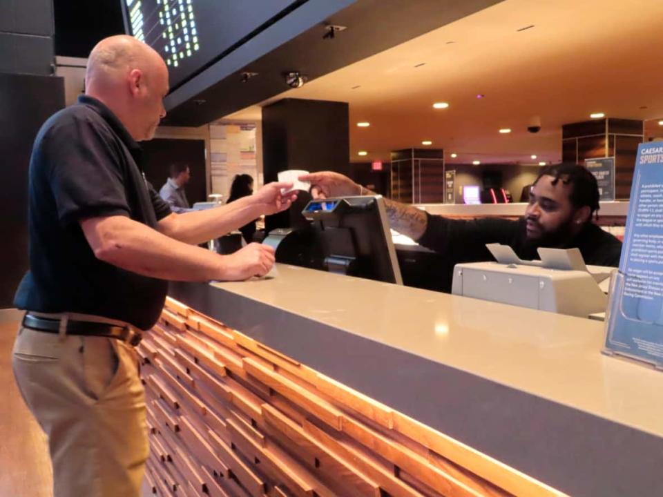 A customer receives a betting ticket in the sports betting lounge at the Tropicana casino in Atlantic City, N.J. in May. Sports betting became legal in Ontario earlier in 2022, among other jurisdictions. (Wayne Parry/The Associated Press - image credit)