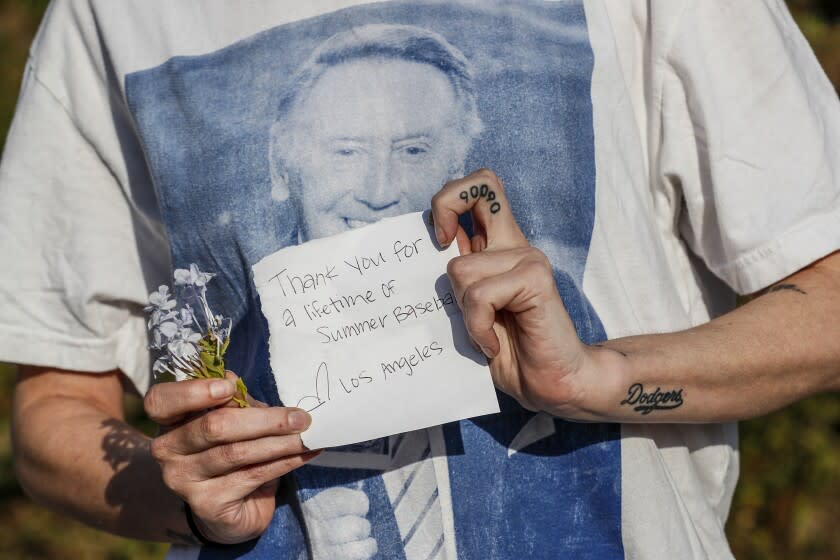 Los Angeles, CA, Wednesday, August 3, 2022 - Dodgers fan Meagan Newhouse shows a note and flowers she would leave at a shrine to Dodgers announcer Vin Scully who died Tuesday at age 94. (Robert Gauthier/Los Angeles Times)