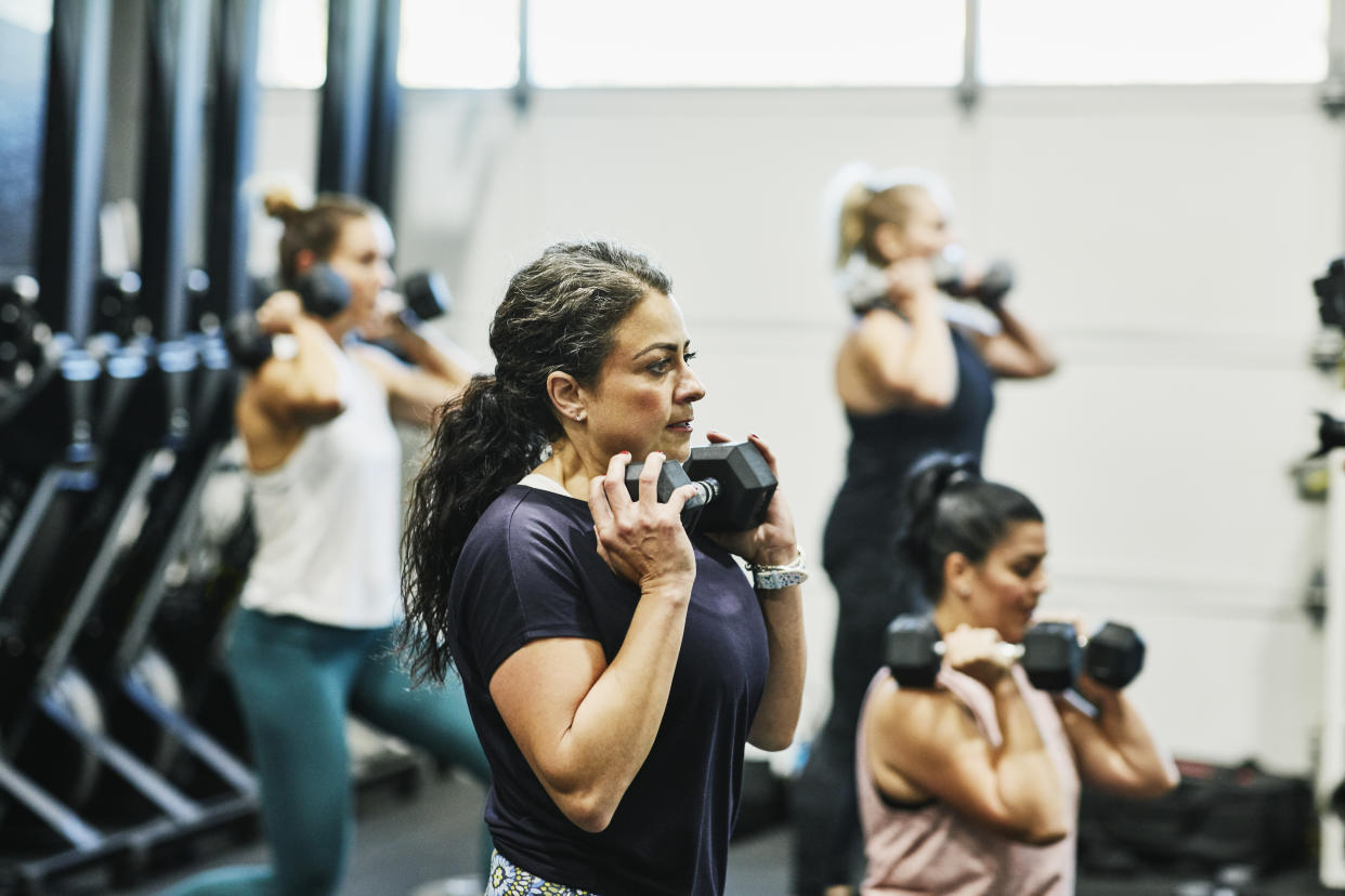 Woman doing dumbbell squats during fitness class in gym. (Getty Images)