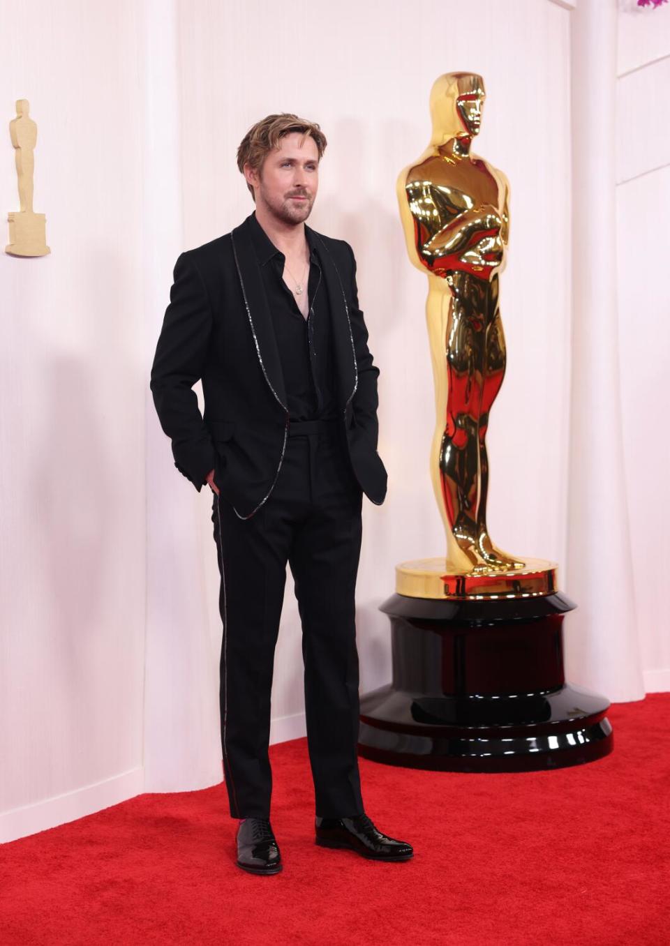 Ryan Gosling wears a black suit with silver trim.