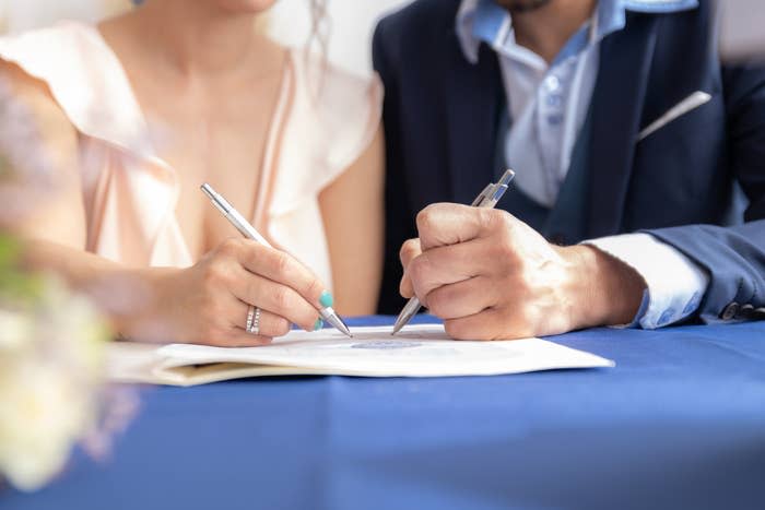 hands signing marriage certificate