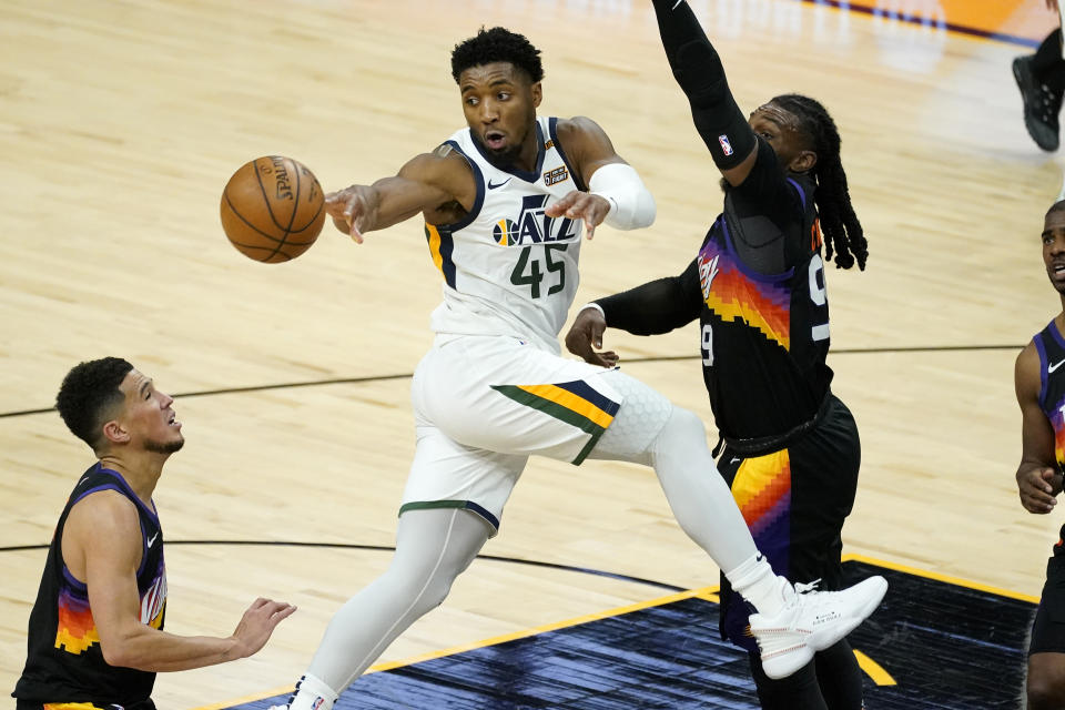 Utah Jazz guard Donovan Mitchell (45) dishes off as Phoenix Suns forward Jae Crowder defends during the second half of an NBA basketball game, Wednesday, April 7, 2021, in Phoenix. (AP Photo/Matt York)