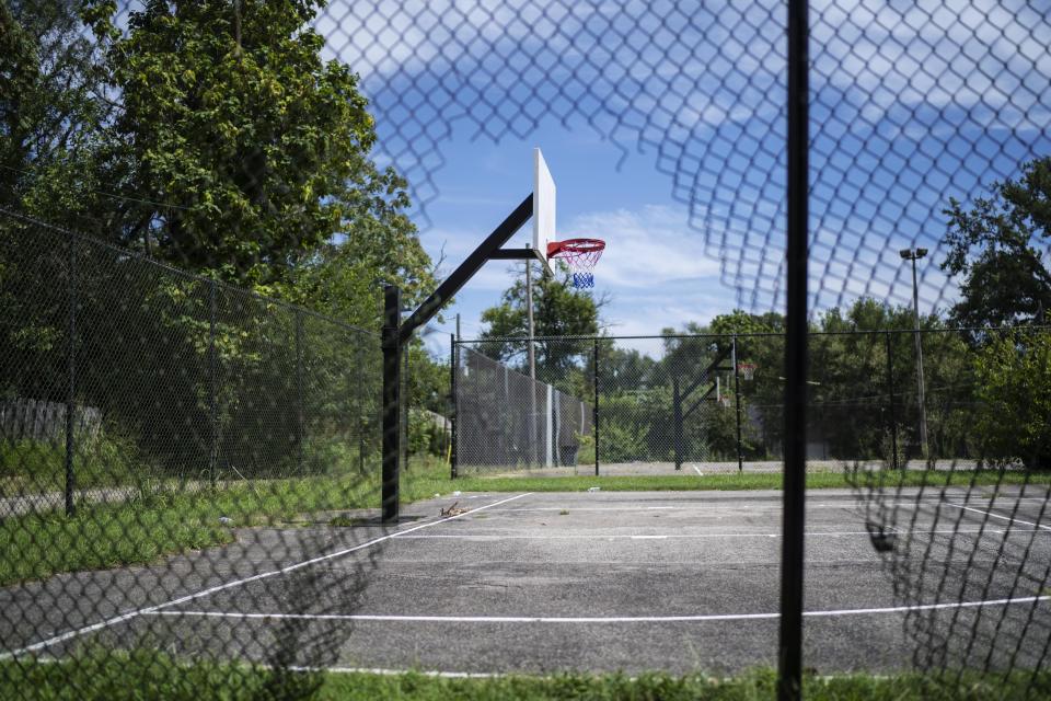A hole in a fence frames a basketball hoop at Ballard Park where Victoria Gwynn was shot and injured in 2021 in Louisville, Ky, Tuesday, Aug. 29, 2023. The 17-year-old friend she was there to meet was killed. Gwynn's brother, Christian, 19, was killed in a drive-by shooting four blocks from home in December 2019. (AP Photo/David Goldman)