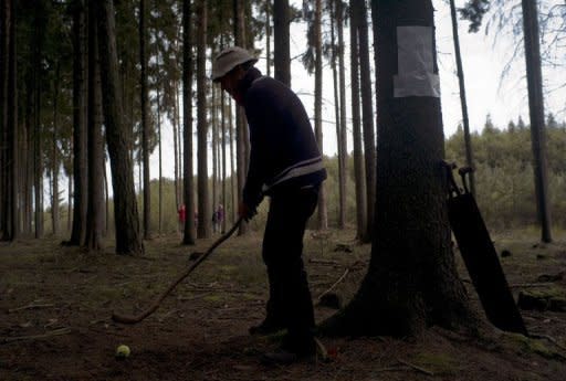 A man prepares to hit a tennis ball as he takes part in a golf tournament in a forest near Uvaly village. A group of Czech "forest golfers" have pioneered a novel approach to an extreme form of golf in the wilds of Bohemia on terrain that would usually be out of bounds on a regular course