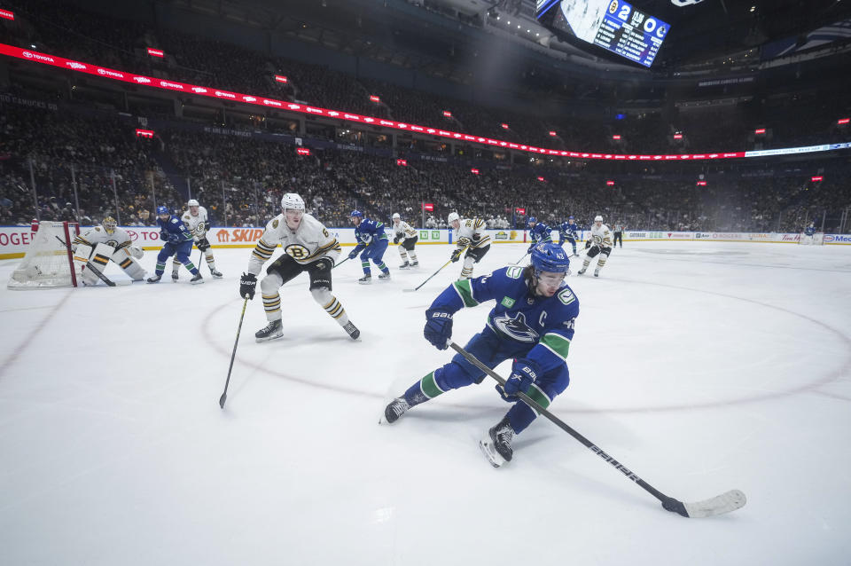 Vancouver Canucks' Quinn Hughes, front right, skates with the puck while watched by Boston Bruins' Mason Lohrei, front left, during the third period of an NHL hockey game in Vancouver, British Columbia, Saturday, Feb. 24, 2024. (Darryl Dyck/The Canadian Press via AP)