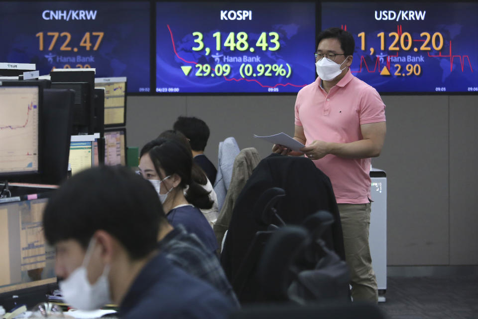 A currency trader passes by screens showing the Korea Composite Stock Price Index (KOSPI), center, and the foreign exchange rate between U.S. dollar and South Korean won, right, at the foreign exchange dealing room of the KEB Hana Bank headquarters in Seoul, South Korea, Friday, April 23, 2021. Asian stock markets were mixed Friday after Wall Street fell following a report that President Joe Biden will propose raising taxes on wealthy investors. (AP Photo/Ahn Young-joon)