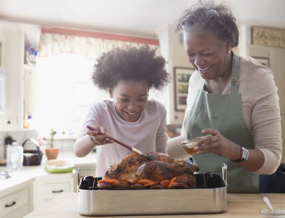 older woman and granddaughter cooking together in kitchen