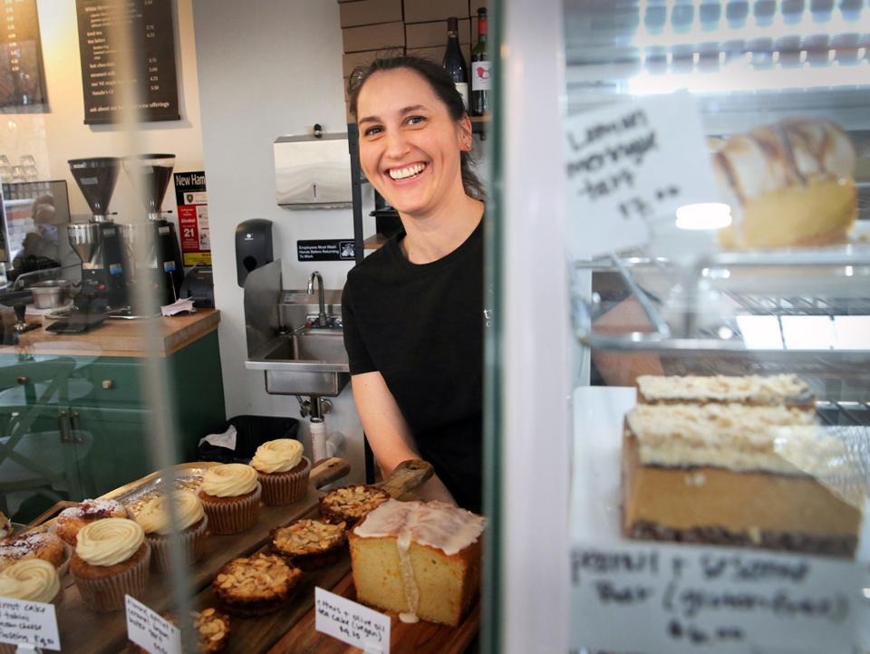 Rebekah Krieger, chef and owner of Two Bees Café + Patisserie in Dover, peeks around a chilled display case after putting fresh pastry inside.