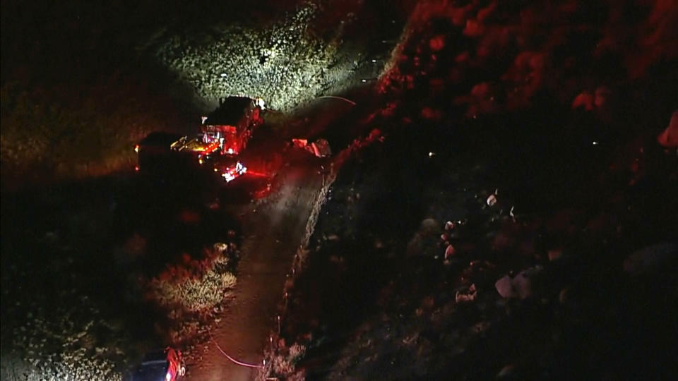 This aerial image taken from video provided by ABC7 Los Angeles shows the scene of a firefighting helicopter crash, with emergency vehicles at the base of a mountain and the area blocked off with police tape, in Cabazon, Calif., Sunday, Aug. 6, 2023. Three people were killed after two firefighting helicopters collided in Southern California on Sunday while fighting a blaze in Riverside County, emergency officials said. (ABC7 Los Angeles via AP)