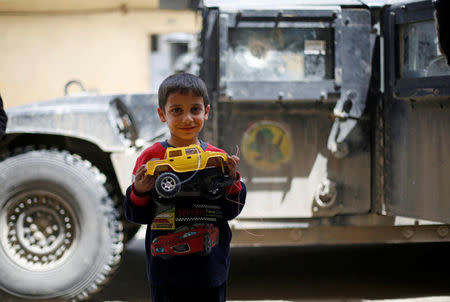 An Iraqi boy poses with his toy in front of a military vehicle after the battle between the Iraqi Counter Terrorism Service and Islamic State militants in western Mosul, Iraq, April 22, 2017. REUTERS/Muhammad Hamed