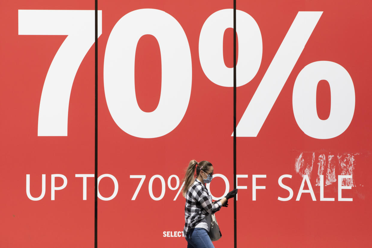 LONDON, ENGLAND  - MAY 19: A woman wearing a face mask walks past a sale sign on Oxford Street on May 19, 2020 in London, England. As shops gear up to open after a long period of closure, clothing stores are beginning to prepare to open their doors, and analysts have suggested that big discounts could be on offer as out of season stock is cleared. The British government has started easing the lockdown it imposed two months ago to curb the spread of Covid-19, abandoning its 'stay at home' slogan in favour of a message to 'be alert', but UK countries have varied in their approaches to relaxing quarantine measures. (Photo by Dan Kitwood/Getty Images)