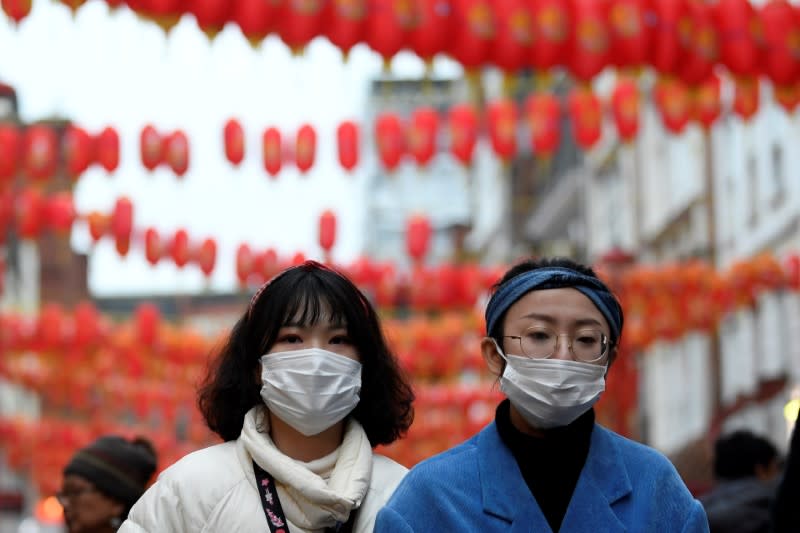 People wear masks as they walk in Chinatown district, in London