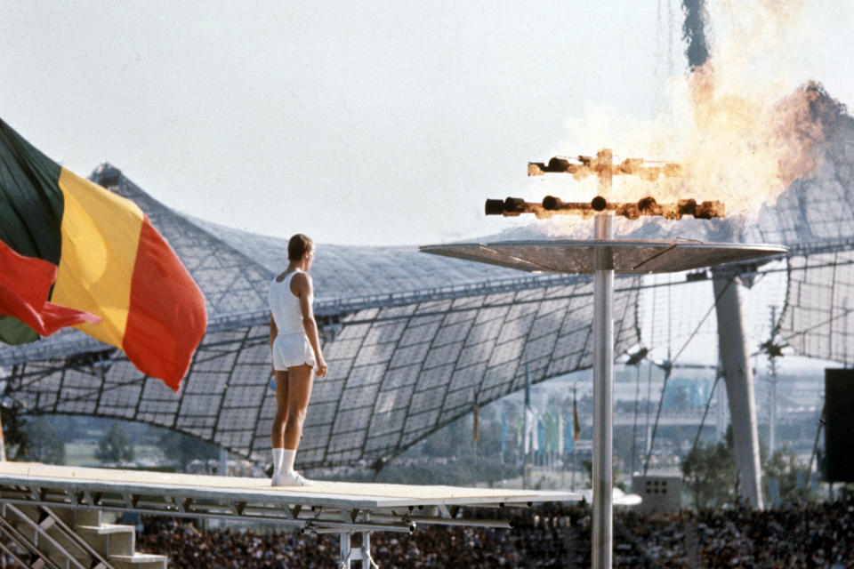 FILE - In this Aug. 26, 1972, file photo, West German middle distance runner, junior athlete Guenther Zahn (18), stands near the Olympic flame he lit above the Olympic Stadium during the opening ceremony of the Summer Olympic Games in Munich, Germany. (AP Photo/File)