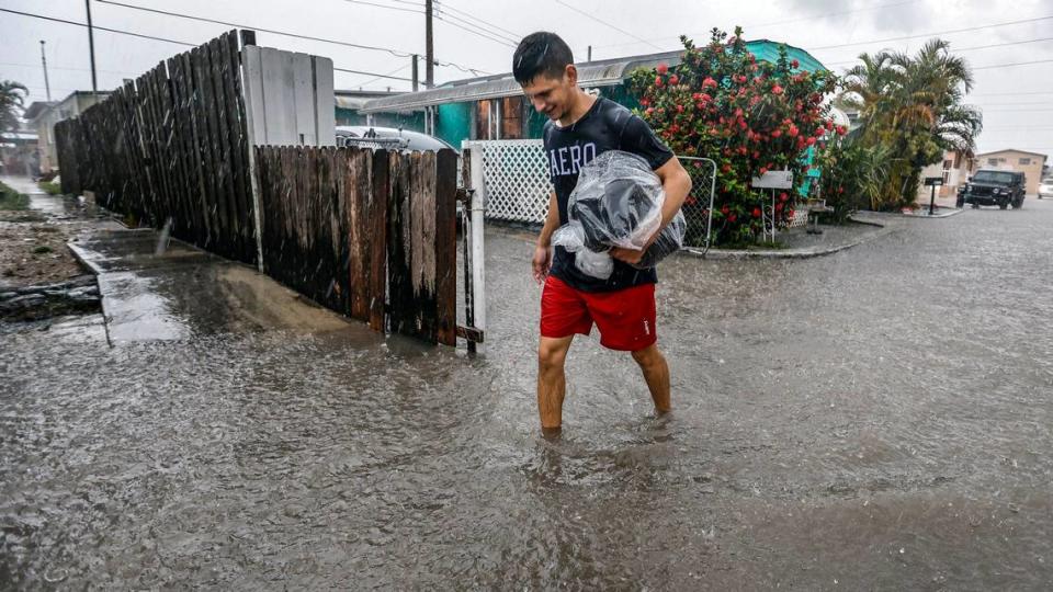 Davie Moreno camina por una calle inundada en Holiday Acres Mobile Home Park en Hialeah, Florida, el miércoles 12 de junio de 20