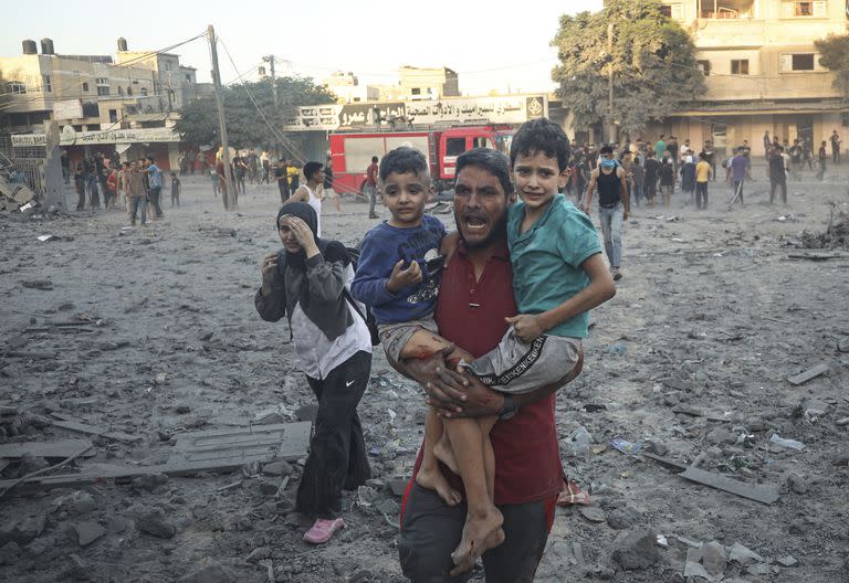 Un hombre con dos niños en brazos se aleja después del ataque aéreo israelí en Rafah, Franja de Gaza, martes 7 de noviembre de 2023. 