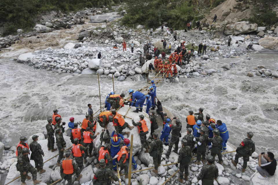 In this photo released by Xinhua News Agency, rescuers build a bridge to transfer villagers through a river following an earthquake in Moxi Town of Luding County, southwest China's Sichuan Province Tuesday, Sept. 6, 2022. Authorities in southwestern China's Chengdu have maintained strict COVID-19 lockdown measures on the city of 21 million despite a major earthquake that killed dozens of people in outlying areas. (Ye Xiaolong/Xinhua via AP)