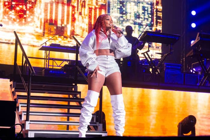 Mary J. Blige onstage wearing a cropped jacket, shorts, and over-the-knee boots