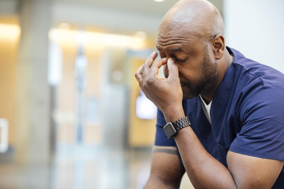 Person looking stressed with hand on forehead, sitting indoors