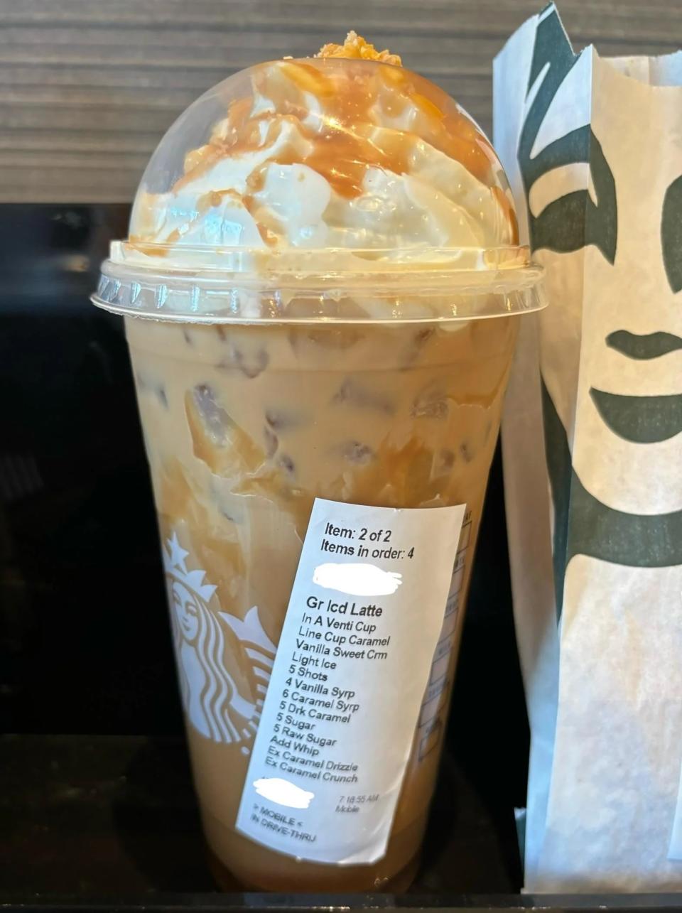 Iced latte with caramel drizzles in a clear cup, custom order sticker visible
