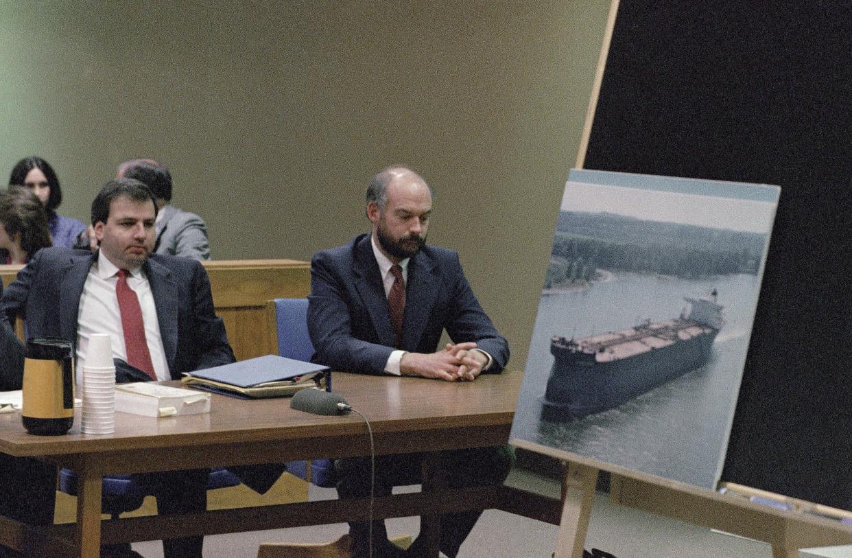 FILE - Fired Exxon Valdez skipper Joseph Hazelwood, right, sits with his lawyer Michael Chalos as a photograph of the tanker is displayed on an easel in Anchorage Superior Court, March 20, 1990. 