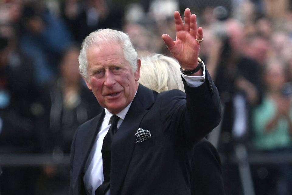 King Charles III and Britain's Camilla, Queen Consort greet the crowd upon their arrival Buckingham Palace