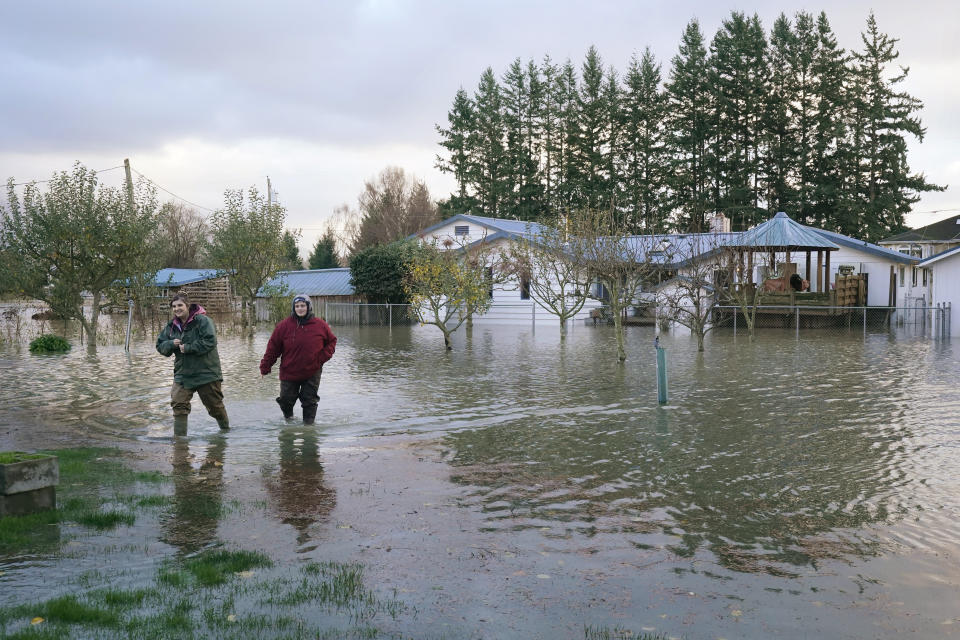 Sisters Myranda, left, and Krysten Archer walk through floodwater from their uncle's home Monday, Nov. 15, 2021, in Sedro-Woolley, Wash. The heavy rainfall of recent days brought major flooding of the Skagit River that is expected to continue into at least Monday evening. (AP Photo/Elaine Thompson)