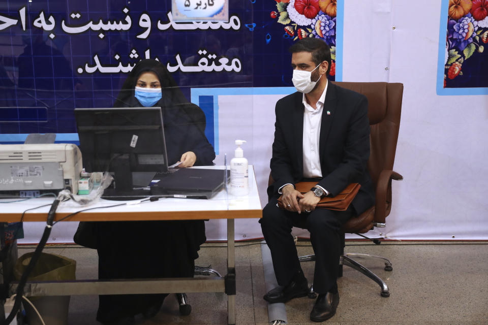 Revolutionary Guard Gen. Saeed Mohammad, right, who once headed the paramilitary force's Khatam al-Anbiya Construction Headquarters, sits as an elections headquarters staff registers his name as a candidate for the June 18, presidential elections at of the Interior Ministry in Tehran, Iran, Tuesday, May 11, 2021. Iran opened registration Tuesday for potential candidates in the country's June presidential election, kicking off the race as uncertainty looms over Tehran's tattered nuclear deal with world powers and tensions remain high with the West. (AP Photo/Vahid Salemi)