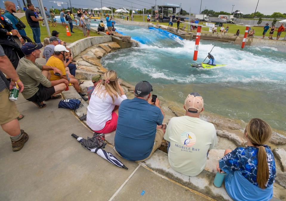 Spectators watch as kayakers compete in the Kayak Cross during the opening weekend at Montgomery Whitewater in Montgomery, Ala., on Saturday July 8, 2023.