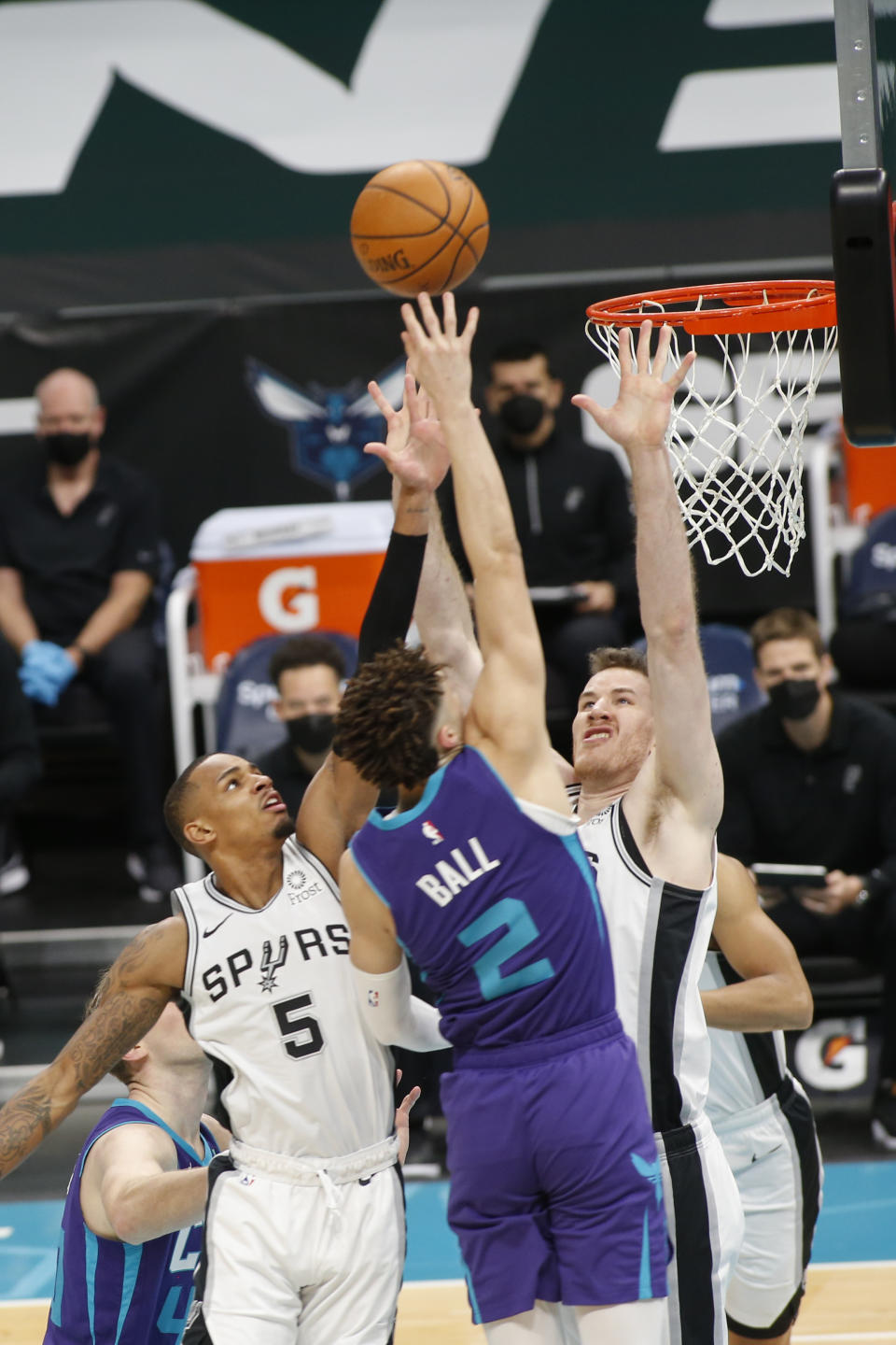 Charlotte Hornets guard LaMelo Ball, center, drives into San Antonio Spurs guard Dejounte Murray (5) and San Antonio Spurs center Jakob Poeltl during the first half of an NBA basketball game in Charlotte, N.C., Sunday, Feb. 14, 2021. (AP Photo/Nell Redmond)