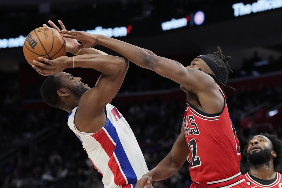 Chicago Bulls guard Ayo Dosunmu (12) reaches in on Detroit Pistons guard Alec Burks during the first half of an NBA basketball game, Wednesday, March 1, 2023, in Detroit. (AP Photo/Carlos Osorio)