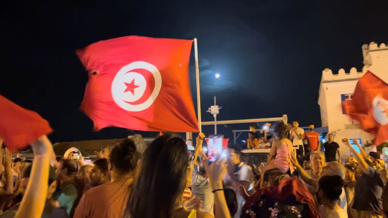 People react in the street after Tunisia's president dismissed government and froze parliament, in La Marsa