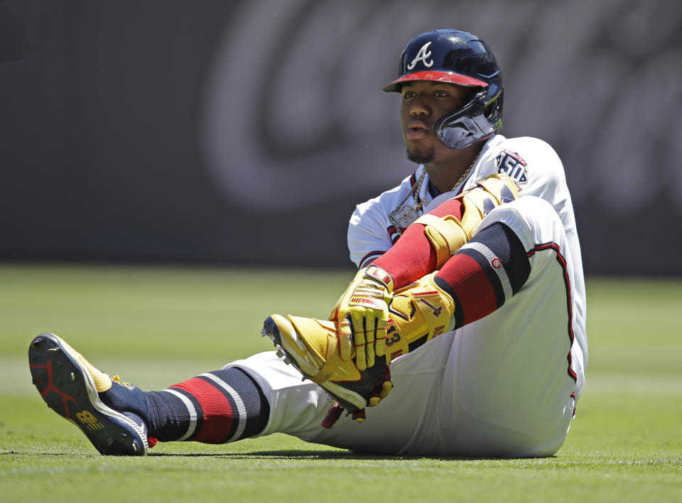 Atlanta Braves' Ronald Acuna Jr. grabs his left foot after falling in the seventh inning of a baseball game against the Toronto Blue Jays on Thursday, May 13, 2021, in Atlanta. (AP Photo/Ben Margot)