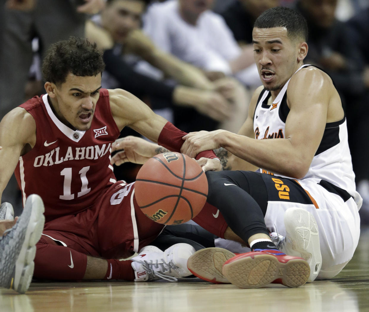 Oklahoma guard Trae Young (11) goes to the floor for a loose ball with Oklahoma State guard Jeffrey Carroll, right, during the first half of an NCAA college basketball game in first round of the Big 12 men’s tournament in Kansas City, Mo., Wednesday, March 7, 2018. (AP Photo/Orlin Wagner)