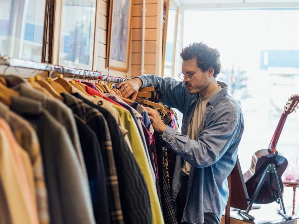 A man looking through second hand clothes at a charity shop in Newcastle-upon-Tyne. According to academics people should limit themselves to buying three new items of clothing a year (Getty)