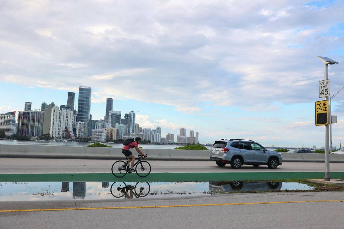 A biker rides near the spot that two cyclists were killed at the foot of the William Powell Bridge on the Rickenbacker Causeway leading to Virginia Key in Miami on May 16, 2022.