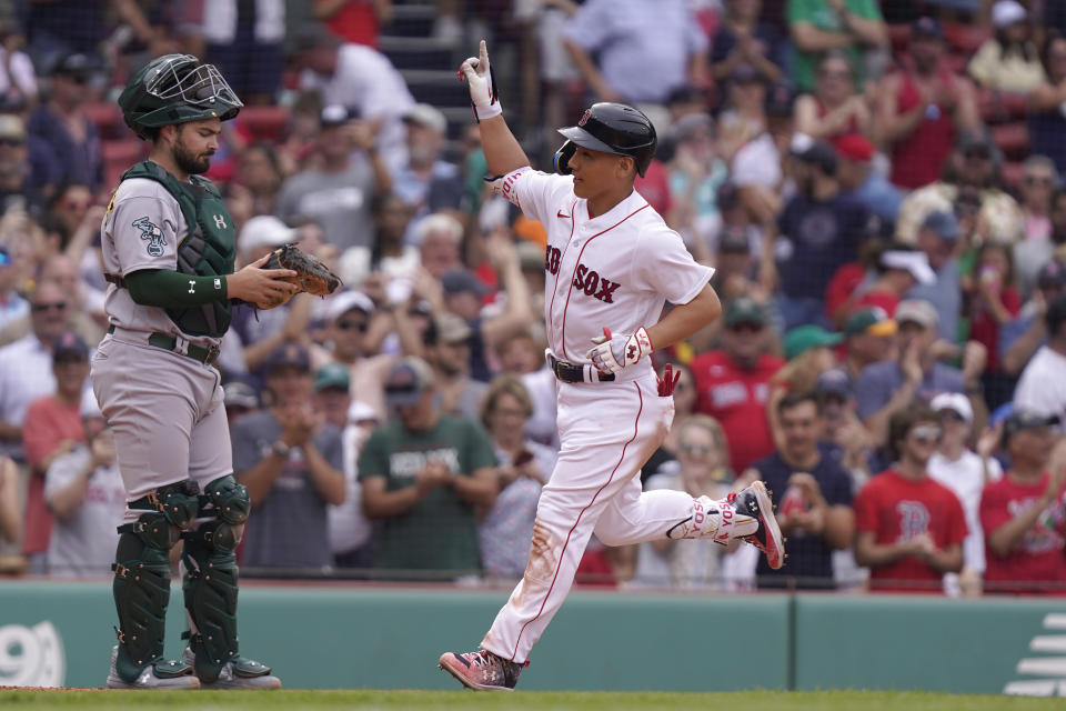 Boston Red Sox's Masataka Yoshida, right, celebrates after his home run as he arrives home in front of Oakland Athletics' Manny Pina, left, in the eighth inning of a baseball game, Sunday, July 9, 2023, in Boston. (AP Photo/Steven Senne)