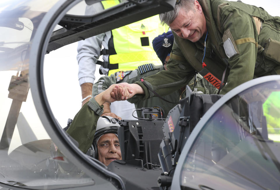 Indian Defense Minister Rajnath Singh shakes hands with chief pilot Philippe Duchateau, right, as he sits in a Rafale jet fighter during an handover ceremony at the Dassault Aviation plant in Merignac, near Bordeaux, southwestern France, Tuesday, Oct. 8, 2019. France has delivered to India its first Rafale fighter jet from a series of 36 aircraft purchased in a multi-billion dollar deal in 2016. (AP Photo/Bob Edme)