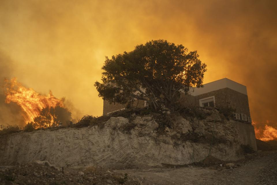 A wildfire burns in Gennadi village, on the Aegean Sea island of Rhodes, southeastern Greece, on Tuesday, July 25, 2023. A firefighting plane has crashed in southern Greece, killing both crew members, as authorities are battling fires across the country amid a return of heat wave temperatures. (AP Photo/Petros Giannakouris)