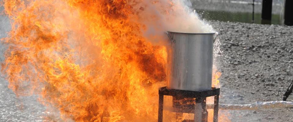 A raging fire occurs after a frozen turkey is placed in an over filled turkey fryer during a safety demonstration.