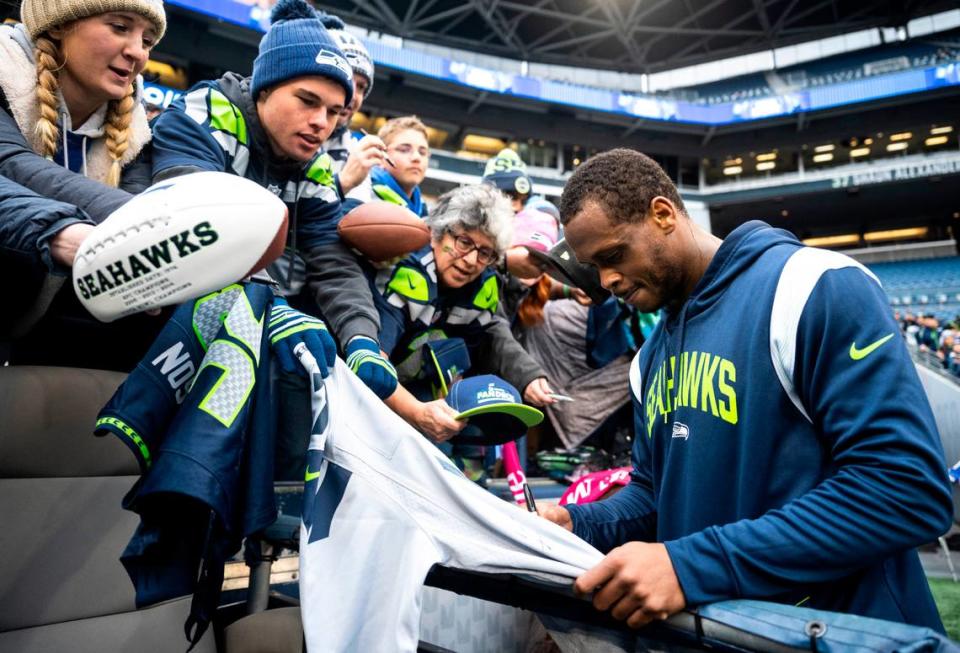 Seattle Seahawks quarterback Geno Smith, 7, signs a fan’s jersey before the start of an NFL game against the New York Jets at Lumen Field in Seattle, Wash. on Jan. 1, 2023.