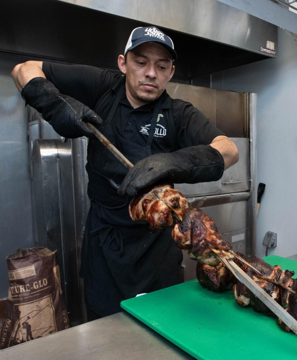 Ronnel Rodriguez removes chicken from the rotisserie at the new second location of Mr. Pollo on Woodbine Road in Pace on Friday, June 30, 2023.