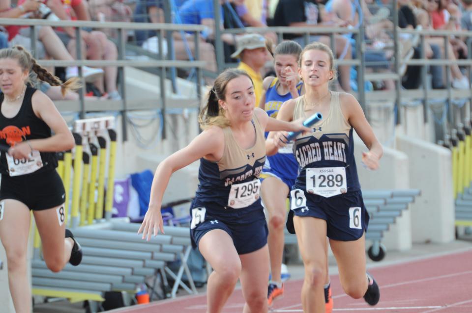 Sacred Heart's Gracy Dorzweiler hands the baton off to Caroline stone during the 1,600-meter relay of the Class 2A state track and field championships Saturday, May 28, 2022 at Cessna Stadium in Wichita.